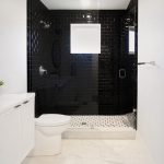 Black and white bathroom; black shower tiles, white floor tiles; white walls; white vanity cabinet